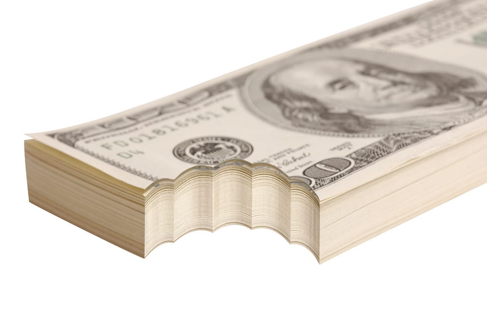 stack of $100 bills with a bite taken out of the bottom left corner of the entire stack