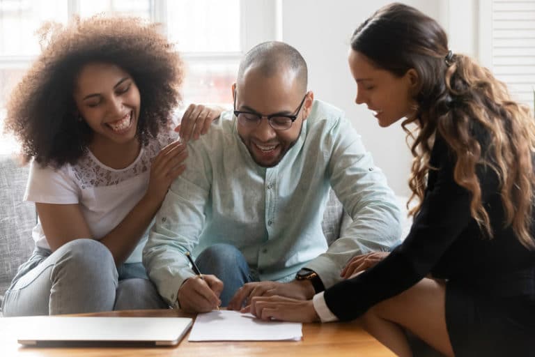 Smiling lawyer showing satisfied couple where to sign documents